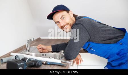 Un installateur travaille sur un évier dans un appartement Banque D'Images
