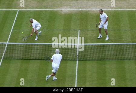 John McEnroe (à gauche) en action avec le partenaire Patrick McEnroe (à droite) contre Paul McNamee (au centre) de l'Australie et Peter McNamara dans le match de Double invitation senior de leurs messieurs au cours du huitième jour de Wimbledon tenu au All England Lawn tennis and Croquet Club Banque D'Images