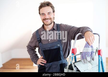 un artisan souriant et attrayant dans les vêtements de travail et avec des outils Banque D'Images