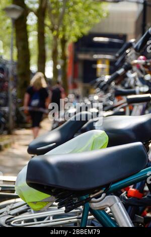 Une rangée de bicyclettes différentes stationnées à l'extérieur dans des casiers à vélos près de la gare principale de Zwolle, aux Pays-Bas. Les gens marchant en arrière-plan. Banque D'Images