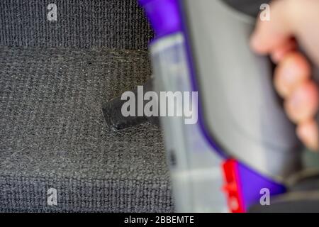 Tenir à la main un aspirateur à main pour éliminer la saleté des escaliers couverts de moquette. Banque D'Images