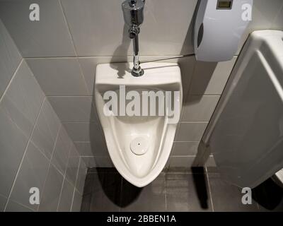 Vue en grand angle de l'urinal d'un homme en porcelaine blanche dans une toilette publique masculine propre Banque D'Images