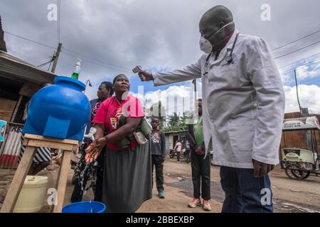 Un docteur, le Dr Fredrick Ochenge mesure la température d'une femme dans une station publique locale de lavage des mains comme mesure de précaution contre la propagation du Coronavirus dans les bidonvilles de Kibera.Kenya les cas de Coronavirus augmentent à 38 comme 7 nouvelles infections sont confirmées. Banque D'Images
