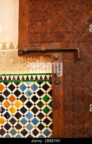 Grenade, Espagne: Vue rapprochée de la porte en bois magnifiquement décorée et des tuiles colorées sur le mur des Myrtles (patio de los Arrayanes) dans Banque D'Images