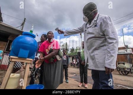 Nairobi, Kenya. 20 mars 2020. Un docteur, le Dr Fredrick Ochenge mesure la température d'une femme dans une station publique locale de lavage des mains comme mesure de précaution contre la propagation du Coronavirus dans les bidonvilles de Kibera.Kenya les cas de Coronavirus augmentent à 38 comme 7 nouvelles infections sont confirmées. Crédit: Donwilson Odhiambo/SOPA Images/ZUMA Wire/Alay Live News Banque D'Images
