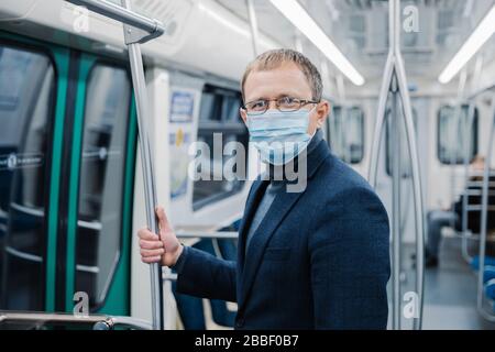 Le tir de jeune homme porte des lunettes et un masque protecteur pour empêcher la propagation de la maladie du coronavirus ou de l'épidémie de grippe dans les transports publics, pose à l'emp Banque D'Images