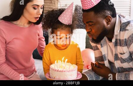 Enfants anniversaire les parents internationaux aident à souffler des bougies Banque D'Images