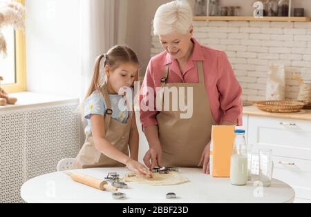 Grand-mère avec sa petite petite petite fille mignonne faisant des biscuits dans la cuisine ensoleillée Banque D'Images