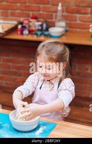 Petite fille pétrir la pâte pour cuire le gâteau. Enfant prenant part à l'atelier de cuisson. Cours de cuisson pour enfants, aspirant petits chefs. Apprentissage Banque D'Images