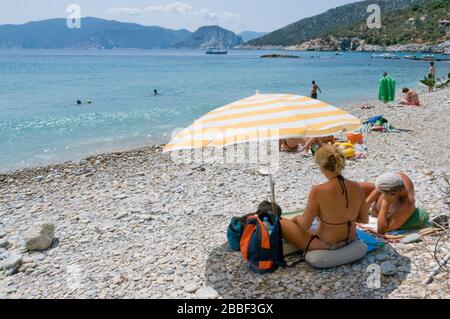 Les amateurs de bains de soleil se reaxent sur la plage de galets de Paralia Megalos Mourtias Alonisos, Grèce Banque D'Images