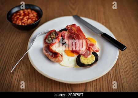 Petit déjeuner friture anglaise complète saucisse œuf bacon champignons haricots café cuillère graisseux gril Banque D'Images