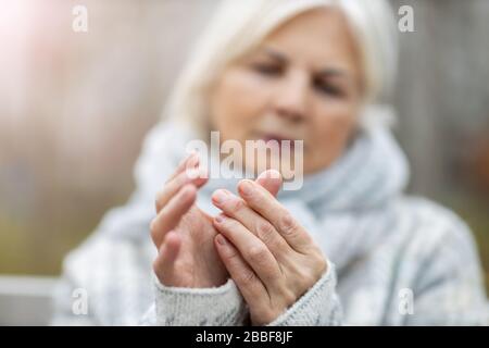 Femme senior avec arthrite frottant les mains Banque D'Images