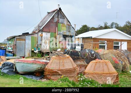 Ushuaia, Argentine-février 2019: Petite maison de pêcheurs avec des équipements de pêche dispersés et des filets à Puerto Almanza le long de la Manche de Beagle près de Banque D'Images