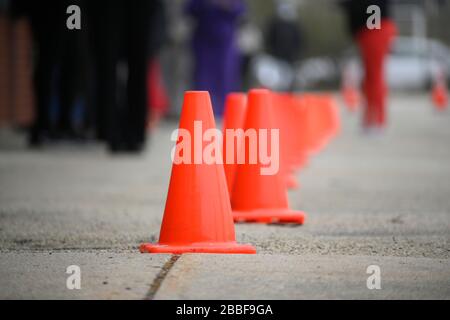 Philadelphie, États-Unis. 30 mars 2020. Les cônes de mini-trafic fournissent une indication de l'espace social ou physique à distance des membres de la communauté qui attendent en ligne à un endroit de distribution libre de nourriture, à Philadelphie, PA, le 30 mars 2020. Le programme coordonné par la Ville distribue deux fois par semaine des boîtes de nourriture gratuites à vingt endroits dans toute la ville aux résidents qui sont à l'origine de la crise COVID-19. Crédit : OOgImages/Alay Live News Banque D'Images