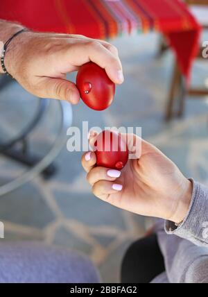 Les mains tenant des œufs de Pâques rouges fissuré - tradition grecque orthodoxe des œufs de craquage - symbolise la résurrection du Christ Banque D'Images