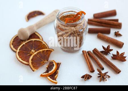 Bâtonnets de cannelle, oranges séchées et anis étoilé avec bouteille de sucre brun avec peu de profondeur de champ sur fond blanc. Cuisson des ingrédients Banque D'Images