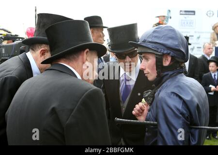 Jockey Ryan Moore (à droite) parle à l'entraîneur Aidan O'Brien (deuxième à droite) après la victoire sur le dirigeant du monde dans le Derby d'Investec Banque D'Images