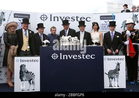 Dirigeant du co-propriétaire mondial Derrick Smith (troisième à gauche) jockey Ryan Moore (quatrième à gauche) copropriétaires John Magnier (centre) et Michael Tabor (quatrième à droite) et entraîneur Aidan O'Brien (deuxième à droite) après la victoire dans le Derby Investec Banque D'Images