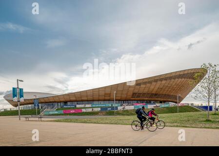 Quelques cyclistes vont devant le centre de cyclisme et le Vélodrome, à l'architecture impressionnante, utilisés lors des jeux olympiques d'été de Londres en 2012 Banque D'Images