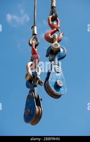 Vue à faible angle d'un système de poulie et de crochet de grue sur un site de construction contre un ciel bleu clair. Banque D'Images