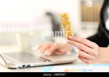 Gros plan sur les mains d'une femme d'affaires avec un ordinateur portable tenant un snack-bar sur un bureau Banque D'Images