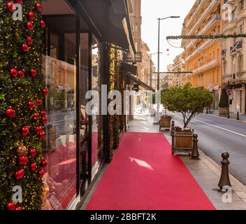 Monaco, Monte Carlo, 25 décembre 2019: La rue à Monaco pour Noël au coucher du soleil, le soleil, les façades décorées de magasins pour des vacances, un rouge Banque D'Images