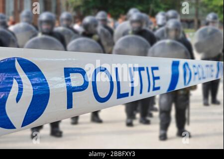 Ruban politié / policier devant l'escadron belge de riot formant une barrière protectrice avec des boucliers de riot en Belgique Banque D'Images