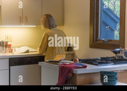 Femme dans la cuisine avec table de cuisson à gaz à quatre brûleurs préparant la soupe de courge musquée Banque D'Images