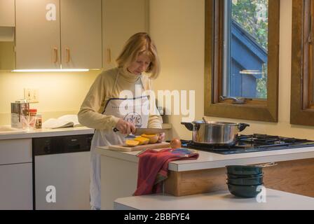 Femme dans la cuisine avec table de cuisson à gaz à quatre brûleurs préparant la soupe de courge musquée Banque D'Images