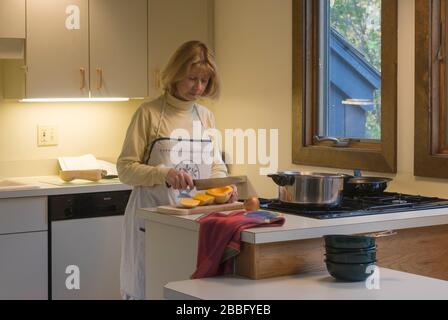 Femme dans la cuisine avec table de cuisson à gaz à quatre brûleurs préparant la soupe de courge musquée Banque D'Images