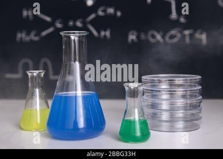 bureau de salle de classe avec flacons avec produits chimiques de couleur, instruments et un tableau noir dessiné avec l'enseignement des sciences en arrière-plan, l'enseignement des sciences chimiques Banque D'Images