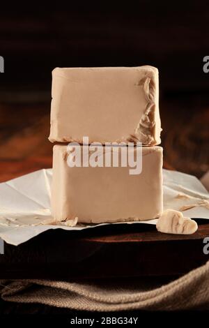 Cubes de levure fraîchement pressés sur une table en bois avec espace de copie. Banque D'Images