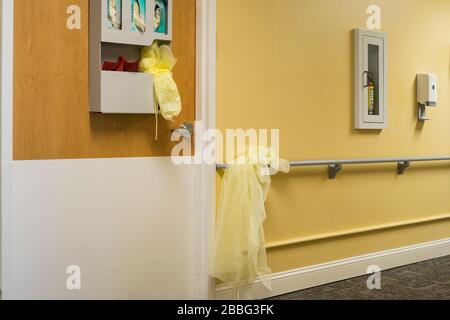 Indiana, États-Unis - 26 mars 2020: Gants et blouses de protection à l'extérieur de la porte de la chambre d'un patient dans un établissement médical. Banque D'Images