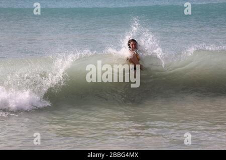 Grande Anse Beach Grenade femme nageant en mer pris dans une vague de rupture Banque D'Images