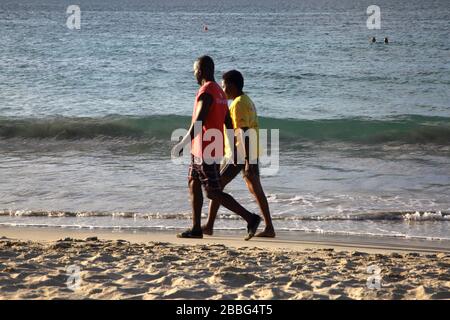 Grenade locaux marchant le long de la plage de Grand Anse Banque D'Images