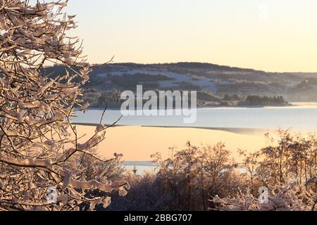 Vue panoramique sur le paysage d'hiver pittoresque avec le lac gelé Selbusjøen mis en évidence par la lumière du soleil dorée, Selbustrand, Norvège. Banque D'Images