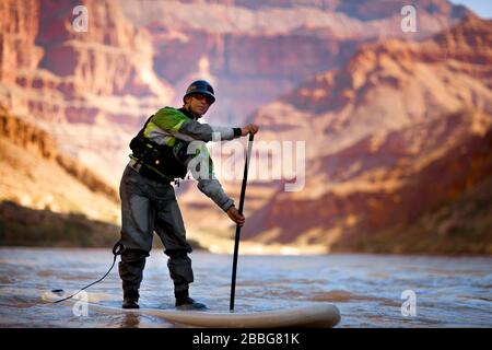 Mid adult man paddleboarding sur une rivière. Banque D'Images