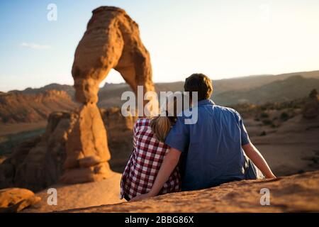 Un jeune couple assis sur un rocher qui regarde sur une vue panoramique Banque D'Images