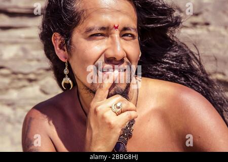 Portrait extérieur de jeune homme à cheveux longs tendance avec bindi et bijoux Banque D'Images
