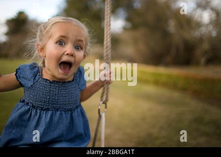 Portrait d'une jeune fille jouant sur un swing dans l'arrière-cour Banque D'Images