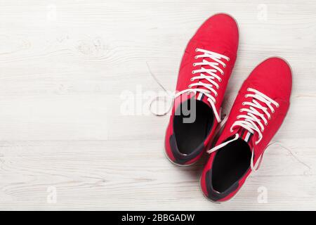Paire de sneakers rouges sur fond en bois avec espace pour votre texte. Vue sur le dessus plat Banque D'Images