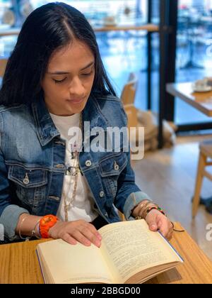 Jolie fille urbaine assise dans un café, livre de lecture, Panama, Amérique centrale Banque D'Images