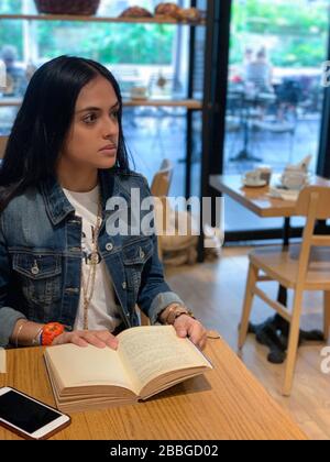 Jolie fille urbaine assise dans un café, livre de lecture, Panama, Amérique centrale Banque D'Images