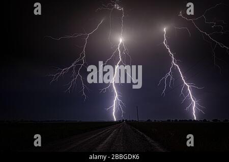 Tempête avec un nuage à portée étroite pour mettre au point des éclairs qui clignotent sur une ancienne route rurale du Kansas, aux États-Unis Banque D'Images