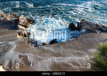 Vagues fortes qui frappent la plage de la ville sur la côte croate. Banque D'Images