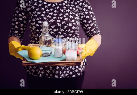 Concept de nettoyants naturels. Femme tenant des ingrédients écologiques pour le nettoyage à la maison, vinaigre blanc, citron, bicarbonate de soude, concept d'acide citrique. Banque D'Images