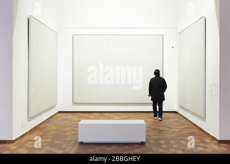 Visiteur devant les peintures du peintre moderniste espagnol Joan Miró intitulée "Peinture sur fond blanc pour la cellule d'un redressement" (1968) affichée dans la Fundació Joan Miró (Fondation Joan Miró) à Barcelone, Catalogne, Espagne. Banque D'Images