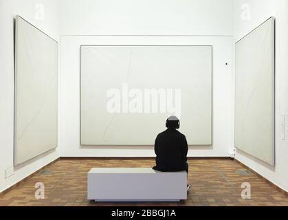 Visiteur devant les peintures du peintre moderniste espagnol Joan Miró intitulée "Peinture sur fond blanc pour la cellule d'un redressement" (1968) affichée dans la Fundació Joan Miró (Fondation Joan Miró) à Barcelone, Catalogne, Espagne. Banque D'Images