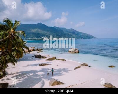 Plage tropicale blanche à Praslin île Seychelles, heureux couple jeune homme et femme pendant les vacances à la plage se détendre sous un palmier Banque D'Images