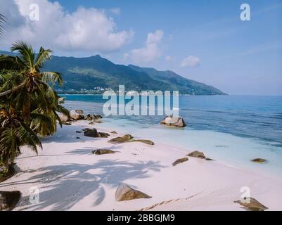 Plage tropicale blanche à Praslin île Seychelles, heureux couple jeune homme et femme pendant les vacances à la plage se détendre sous un palmier Banque D'Images